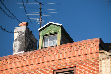 Attic window and chimney closeup on vintage red brick building top