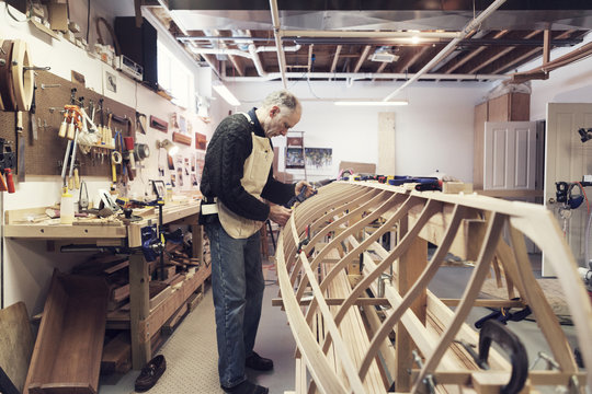 Full length of senior man making boat in workshop