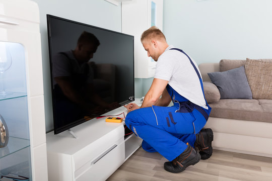 Male Electrician Fixing Television