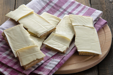 slices of cheese on bread toasts wooden background
