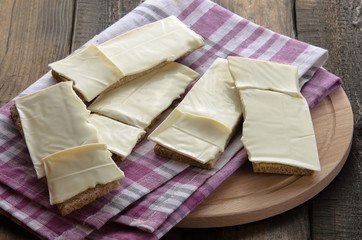 slices of cheese on bread toasts wooden background