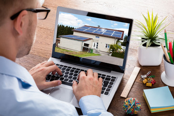 Businessman Looking At House On Laptop