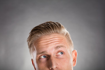 Young Man Looking Up Against Gray Background