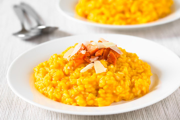 Fresh homemade carrot risotto made with pureed carrot, garnished with roasted carrot and hard cheese, photographed with natural light (Selective Focus, Focus in the middle of the image)