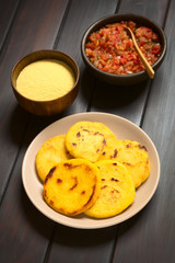 Arepa corn meal patties with Colombian hogao sauce (tomato and onion cooked) and corn meal in the back (Selective Focus, Focus on the first arepas)