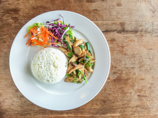 Thai local food Fried mushroom basil and rice on wood table with copy space. top view.