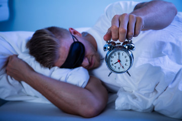 Man Sleeping With A Alarm Clock In His Hand