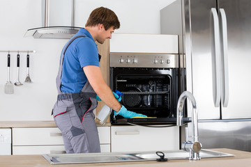 Man In Overall Cleaning Oven