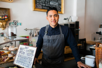 Happy barista standing at his counter