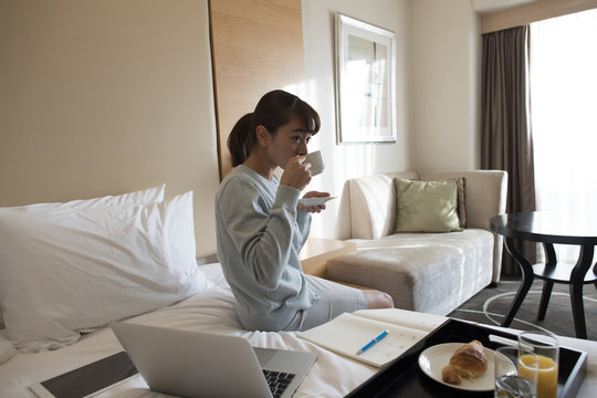 A young lady is drinking coffee at a hotel on a business trip