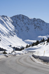 Paved winding road through snow covered mountains