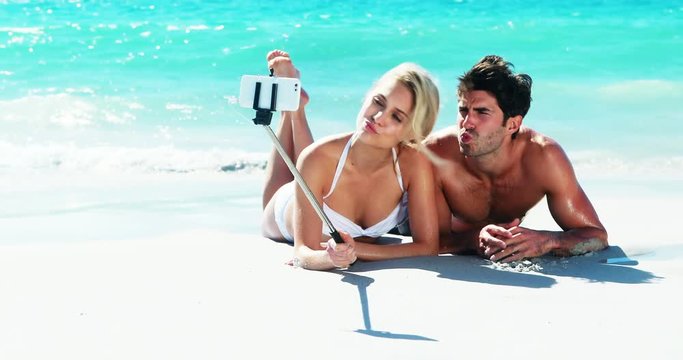Couple lying on beach and taking a selfi from mobile phone