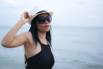 Sexy woman with black dress posing on the beach