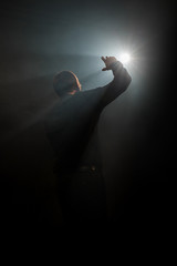 Male singer on dark smoky stage shot from back