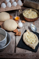 Khachapuri in process. Dough and filling on the wooden board.