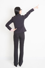 Back view Asian businesswoman pointing away