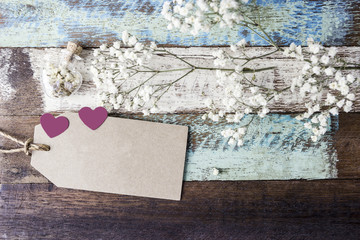 Love concept of blank brown paper tag with heart and flowers on old wood for valentines day and wedding