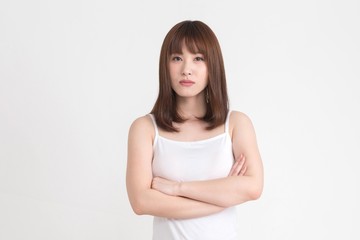 若い女性が、疑問や悩みがあるようなポーズをしています。この画像の背景は、白です。