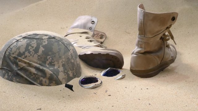 soldier hat  boots and sand glass in the desert
Wreck bulletproof helmet Military boots and goggles sand in the desert It sank in the sand