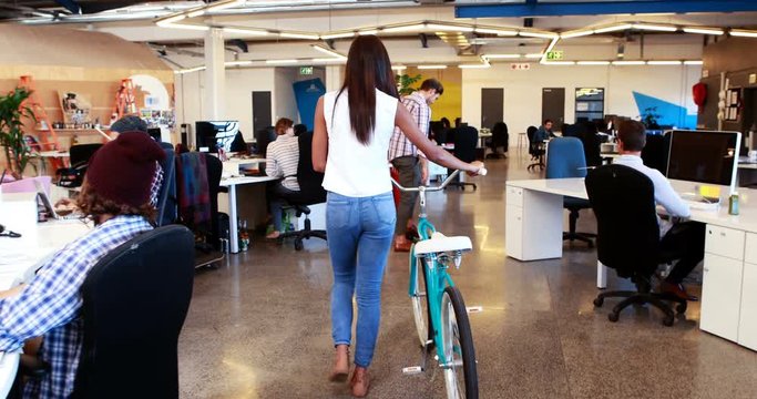 Businesswoman walking with bicycle while businessman using hoverboard