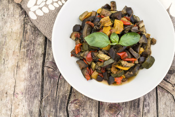 Ratatouille with eggplant, zucchini, red and yellow peppers on wooden background