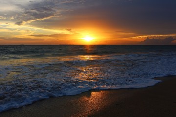 Golden sunset by the sea with soft foam wave