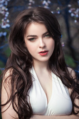 Beautiful girl standing at blossoming tree in the garden