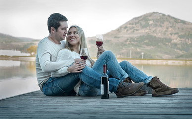 Romantic Couple sitting on the pier with red wine.