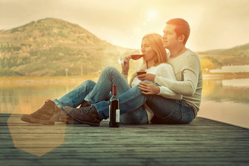 Romantic Couple sitting on the pier with red wine.