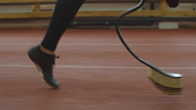 Low section of leg and prosthetic limb of amputee athlete running on track 