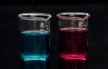 two beakers containing colored solutions