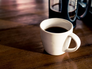 French coffee press with freshly brewed coffee, on wood table