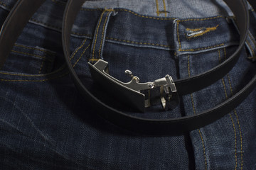 Detail of jeans with black leather belt closeup.