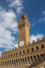 Fototapeta na wymiar Fragment of clock tower of the Old Palace with blue sky. Tuscany. Italy.