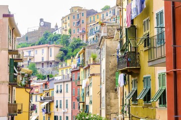 Obraz premium Riomaggiore village, La Spezia, Liguria, northern Italy. Colourful houses on steep hills,castle with clock,laundry on balconies.Part of the Cinque Terre National Park and a UNESCO World Heritage Site.