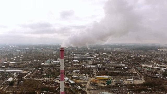 Aerial view of the industrial part of the city. Camera flying near the brick chimney of the heat power plant. 4K