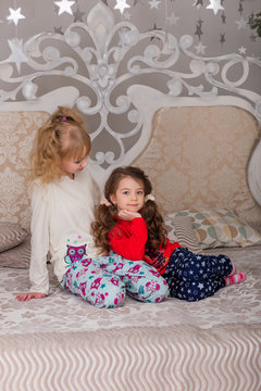  Beautiful children play in their pajamas on the bed before goin