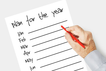 Man writes a plan for the year on the paper sheet