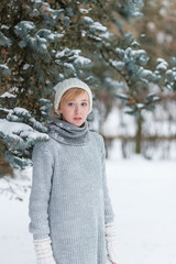Obraz premium Beautiful girl in a white hat and mittens in the winter snowy fo