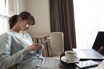 The woman is sitting on a couch and using a tablet