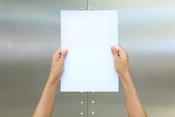 Woman hand holding sheet of paper against metal background.
