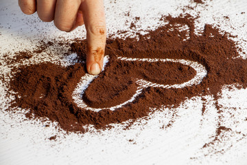 girl draws a heart with her finger in the ground coffee
