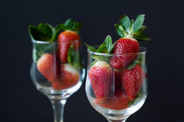 Strawberry with green leaves in vine glasses on black background