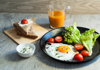 breakfast close-up fried eggs with vegetables and juice. On a wooden background