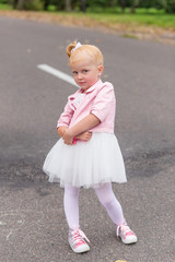 Fototapeta premium A cute little girl in a beautiful dress and sneakers playing on