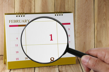 Magnifying glass in hand on calendar you can look first day of m