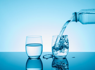 Bottle with creative splashing water in the glass