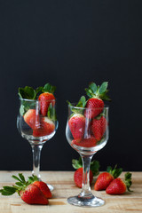 Two vine glasses filled with fresh strawberry on wooden table. Romantic and love concept. Healthy food
