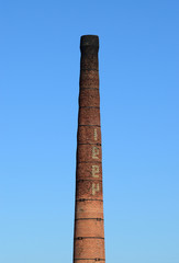 Fototapeta premium brick factory chimney. Tube for propulsion bricks in the furnace. Pipe on a background of blue sky