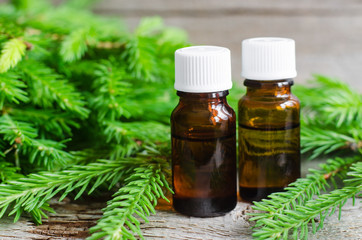 Two bottles of essential oil and fir branches. Aromatherapy and spa products